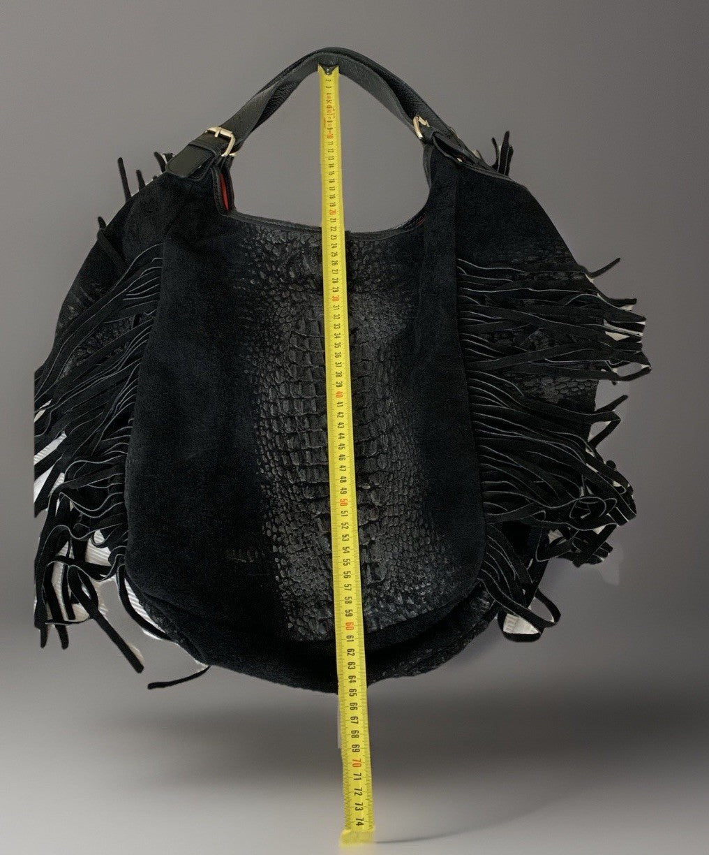 Messung der Höhe der schwarzen Tasche (von oben nach unten) mit einem gelben Maßband.