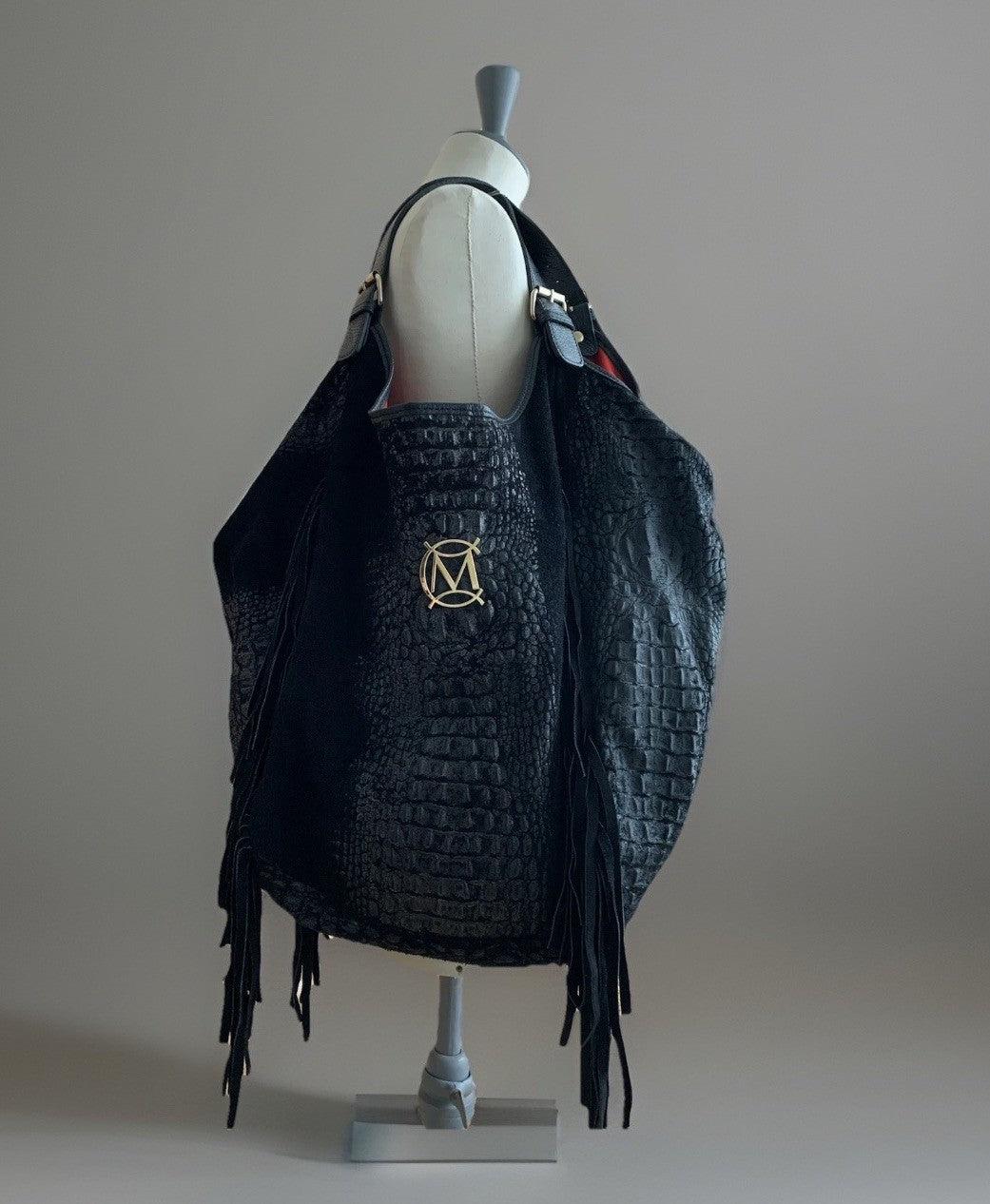 Schwarze Massimo Conti Hobo-Bag mit Kroko-Design und Fransen, präsentiert auf einer Schneiderpuppe.