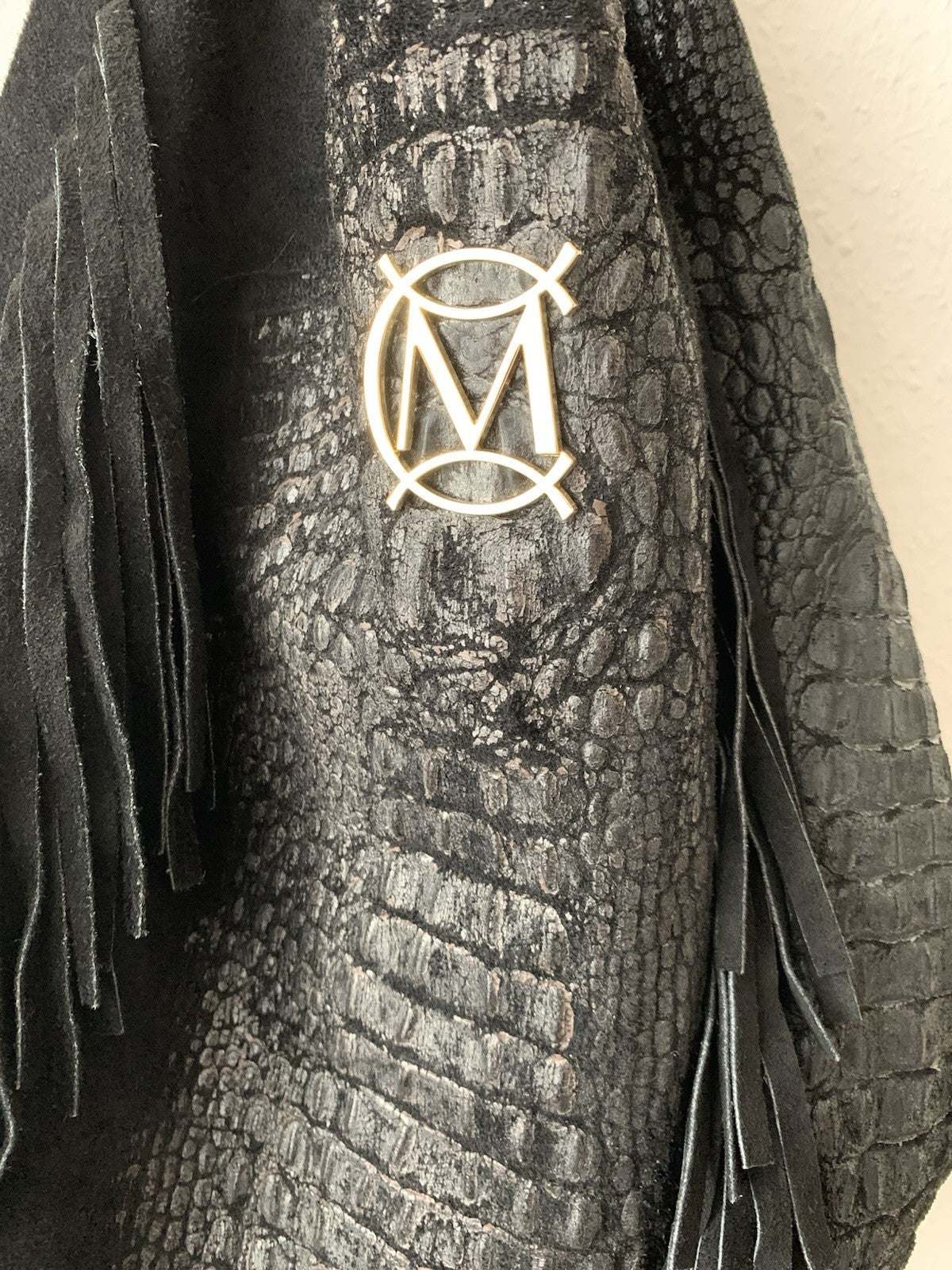 Nahaufnahme des schwarzen Leders mit deutlicher Krokoprägung und Logo.