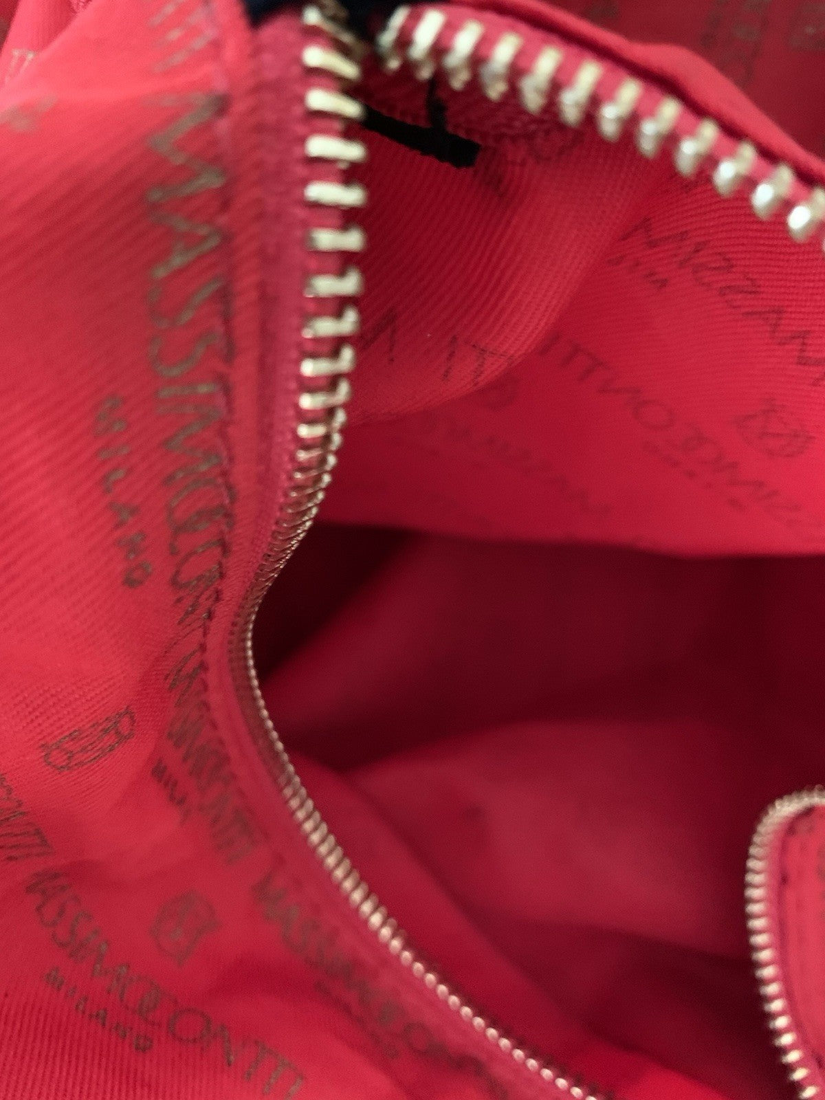 Detailansicht des silberfarbenen Reißverschlusses der Innentasche vor rotem Futter.