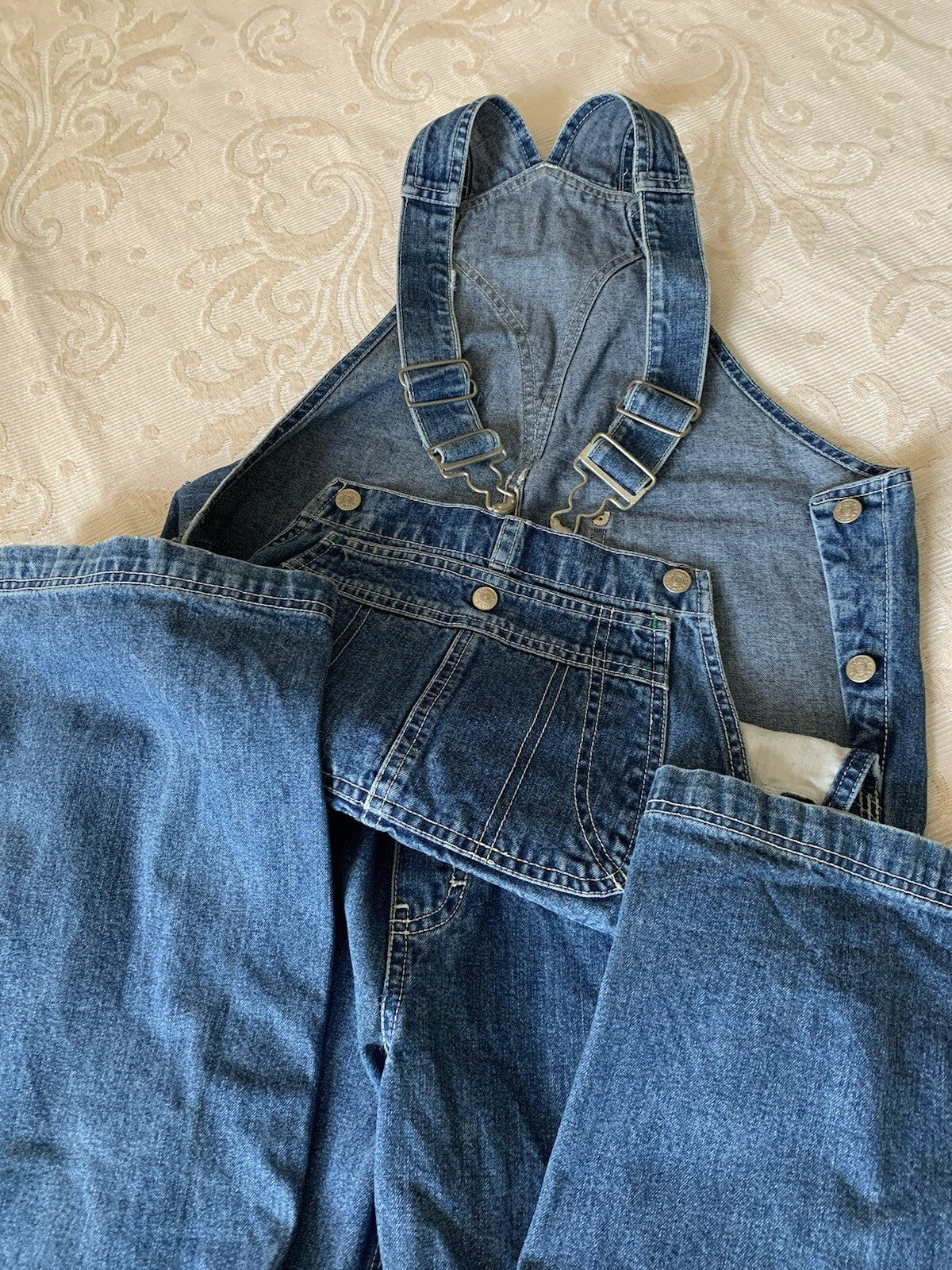 Latzhose flach ausgelegt, blaue Denimfarbe