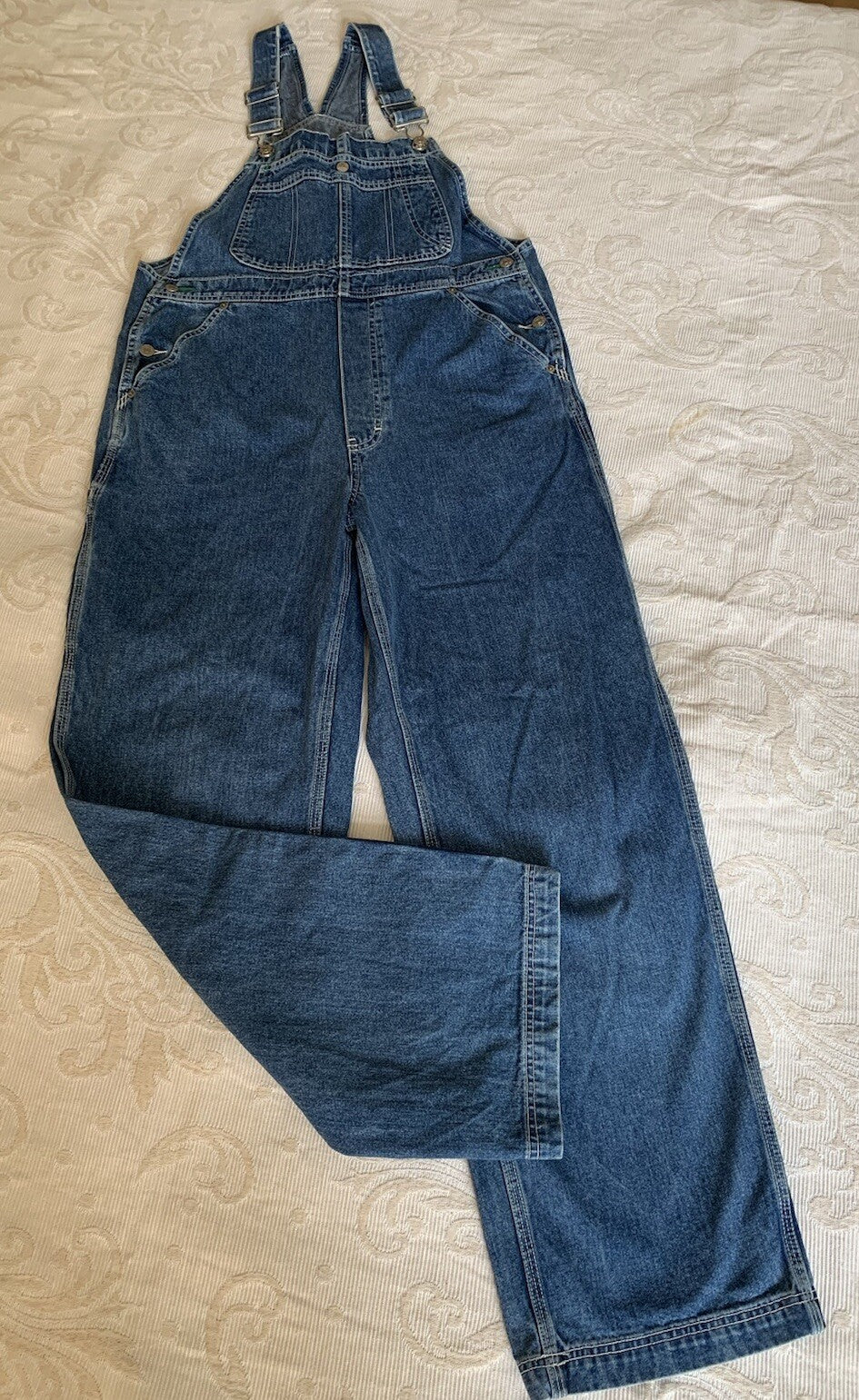 Tommy Hilfiger Latzhose in blauer Denimfarbe in der Frontansicht geknicktes Bein
